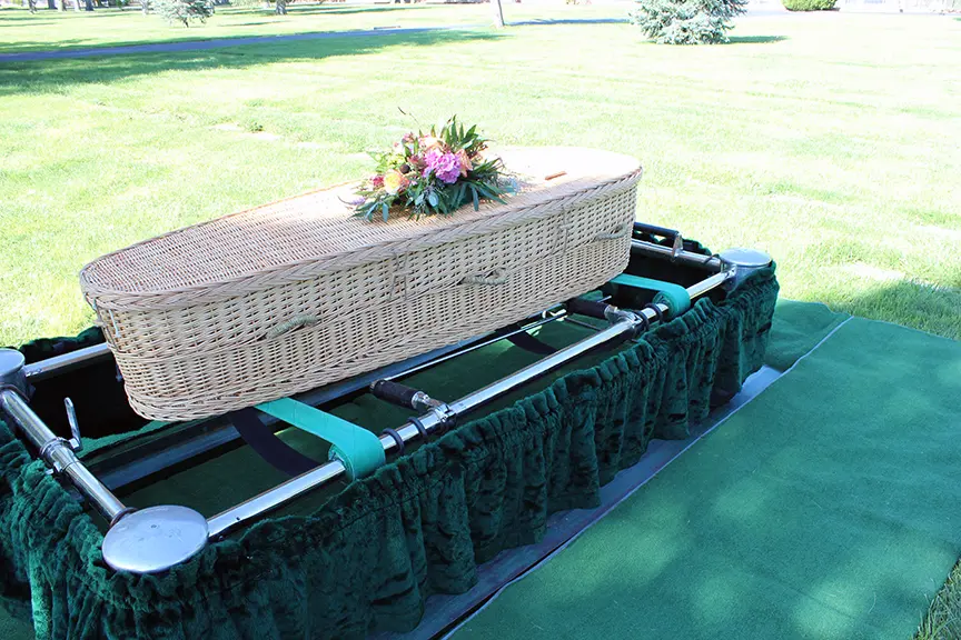 willow casket on stand in cemetery yard.webp